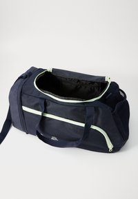 Marine duffel taske med lys grønne accenter. Har en lynlåsåbning, to håndtag og et rummeligt indre. Tekstureret stof med mesh-detaljer.