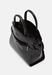 Černá kožená kabelka s hadí texturou, se dvěma uchy, předním klopovým víkem a viditelným logem Calvin Klein na bílém pozadí.