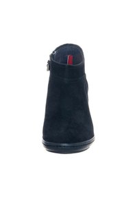 Černé semišové kotníkové boty se zipem na boku, zaoblenou špičkou a malým textilním poutkem v červené a bílé barvě uvnitř límce.