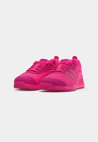 Bright pink athletic shoes with a textured mesh upper, rubber sole, and raised design elements, featuring round laces and branding details.