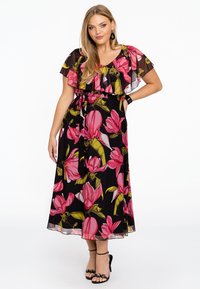 Maxikleid mit schwarzem Grundton, das große pinke und grüne Blumenmuster zeigt. Rüsche Ärmel, taillierter Gürtel und fließender Stoff.
