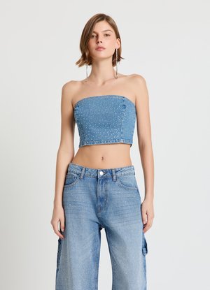 Denim crop top featuring a bandeau design, embellished with small metallic studs. Worn with high-waisted, light blue wide-leg jeans.