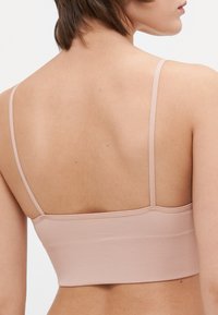 Rosa ribbad bralette med en bred resår och tunna justerbara axelband, som visar en mjuk textur med en åtsittande design.