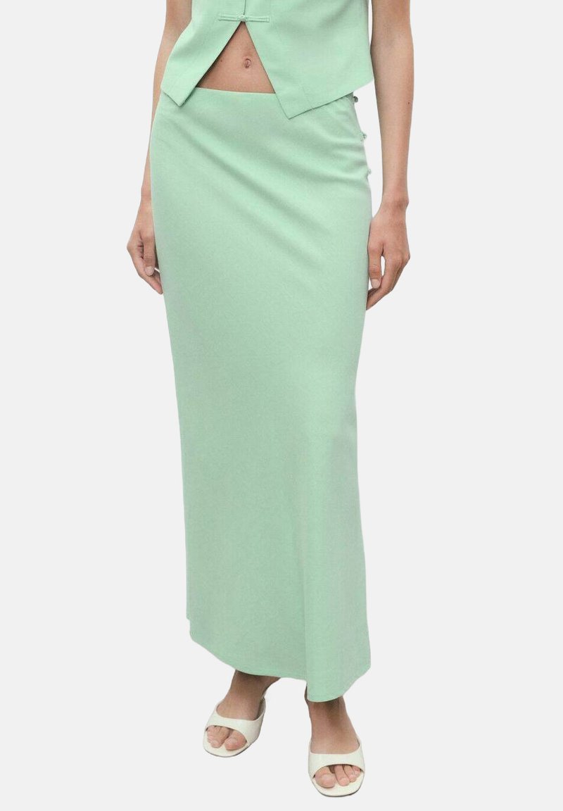 Jupe midi ajustée vert clair avec une texture lisse et un éclat subtil. Elle présente une taille haute et une fente sur le côté pour faciliter le mouvement.