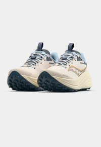 Urheilukengät, joissa on kermaisen värinen päällinen, siniset korostukset ja kuvioitu, kestävä pohja. Varustettu pehmustetulla kauluksella ja nauhoilla varmistamaan napakka istuvuus.