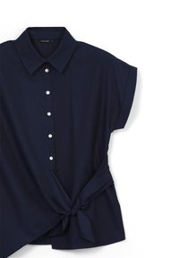 Blusa blu navy a maniche corte con colletto, bottoni frontali e un nodo laterale su sfondo bianco.