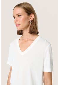 Vit V-ringad t-shirt i mjukt material med korta ärmar, som har en avslappnad passform och minimalistisk design. Slät textur, inga mönster eller detaljer.