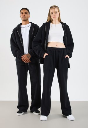 Black oversized hoodies and matching wide-leg pants, featuring a soft texture, drawstring waist, and subtle stitching details.