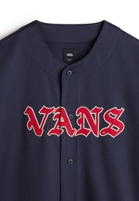 Navy blauwe honkbalshirt met een mesh textuur, voorzien van een rood en wit "VANS" logo over de borst en zwarte knopen. Het label geeft maat M aan.
