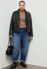 Giacca da motociclista in pelle nera, top marrone, jeans blu con risvolti, stivaletti marroni alla caviglia, borsa nera. Design semplice con vestibilità rilassata.