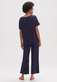 Completo in due pezzi blu navy, composto da una maglietta a maniche corte con bottoni sul retro e pantaloni a gamba larga con un sottile motivo astratto rosa.