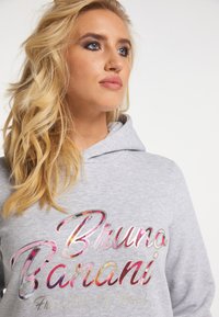 Grijze hoodie met een trekkoord capuchon, voorzien van meerkleurige, glanzende tekst die "Bruno Banani" op de voorkant weergeeft.