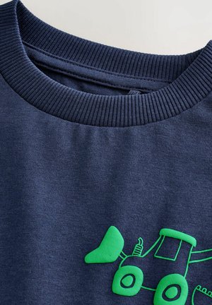 Navyblå sweatshirt med ribbad halsringning; har en ljusgrön traktorgraphik på framsidan; tillverkad av bomull med en slät yta.