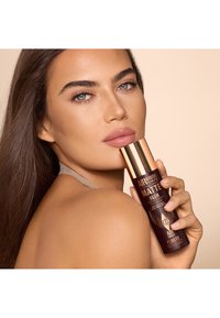 Airbrush matte setting spray in a sleek dark bottle with gold accents. Smooth texture, elegant design, and clear product labeling.