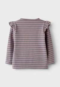 Grå långärmad topp med lila horisontella ränder, med små volanger på axlarna och rund halsringning. Mjuk, stretchy tyg.