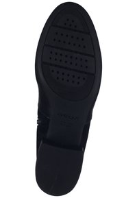 Suola di scarpa nera in gomma testurizzata, con motivi di grip e un piccolo tacco. Logo "GEOX" impresso vicino al tacco.