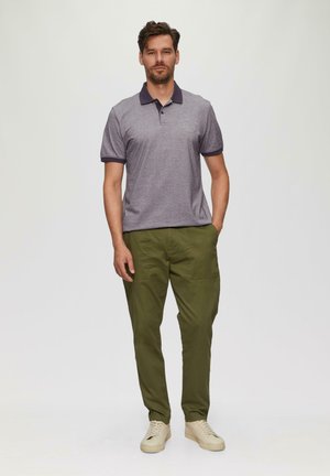 Grau Polohemd mit marineblauem Kragen und Manschetten, mit einem Logo-Print. Kombiniert mit olivgrünen Hosen und hellen Sneakers.