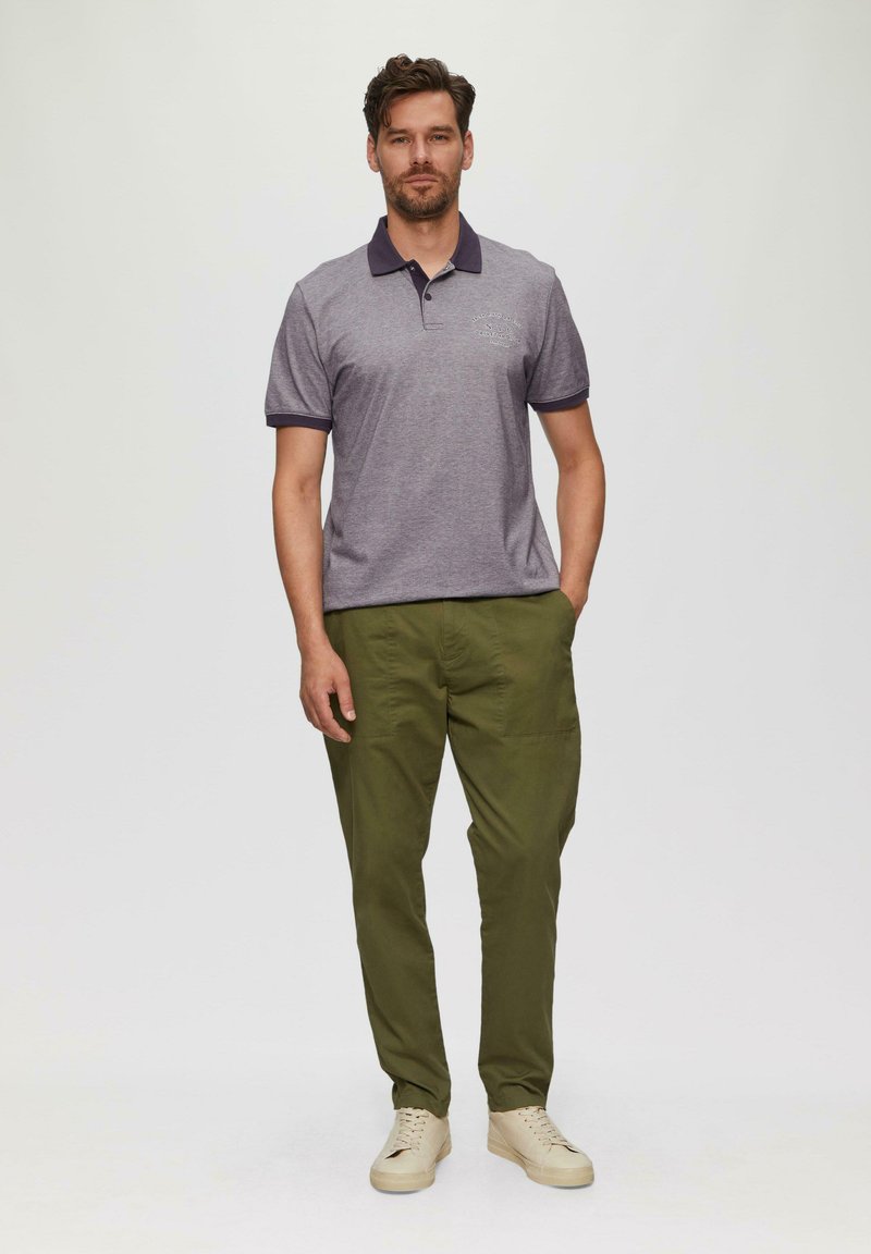 Szary polo z granatowym kołnierzykiem i mankietami, z nadrukiem logo. W połączeniu z oliwkowymi spodniami i jasnymi trampkami.