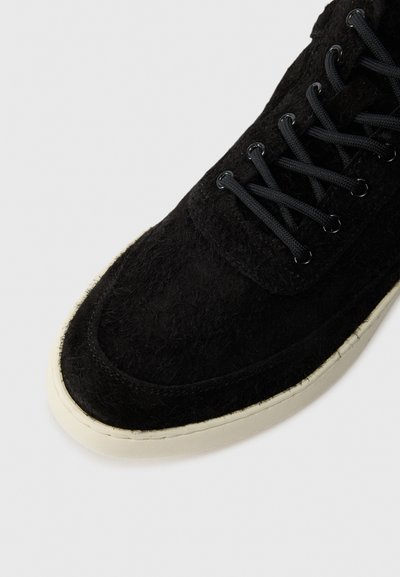 Svart semsket sneakers med teksturert overdel, svarte snørebånd og kremfarget gummisåle. Rund tå og ren sømdetalj.