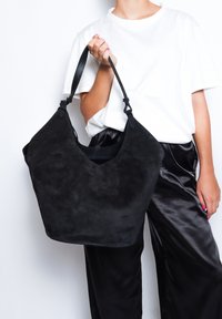 Borsa a spalla nera in suede con un'ampia apertura, forma curvata e due manici. Texture liscia senza motivi visibili o elementi in metallo.