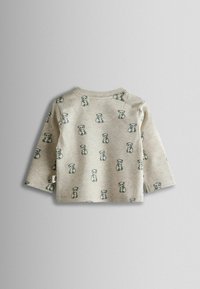 Pikad varrukad shirt heledast beežist kangast, millel on korduvad panda mustrid. Pehme tekstuur, ümmargune kaelus ja õmmeldud ääristuse detailid.