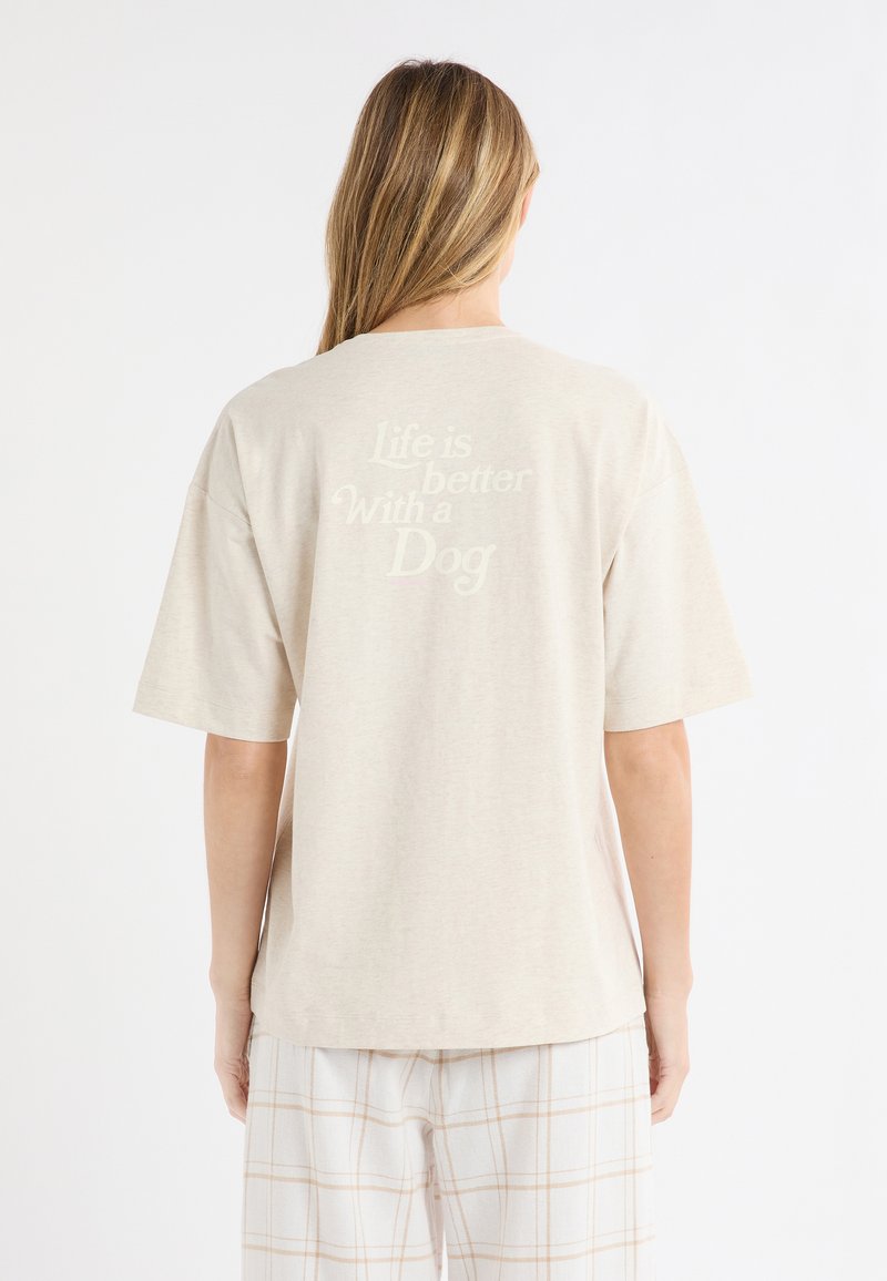 Jasnobeżowa bawełniana koszulka z krótkim rękawem, z centralnie umieszczonym napisem "Życie jest lepsze z psem" w kontrastującym kremowym kolorze.