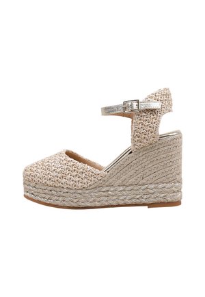 Chaussure laçage beigne avec une tige en tissu texturé, bride métallique ajustable à la cheville et plateforme en corde tressée.