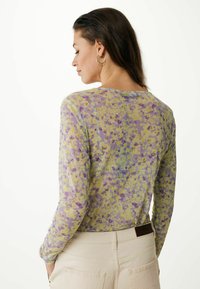 Dlouhý rukáv, průhledný top s květinovým vzorem v purpurových a žlutých odstínech. Lehká tkanina s kulatým výstřihem a upnutými rukávy.
