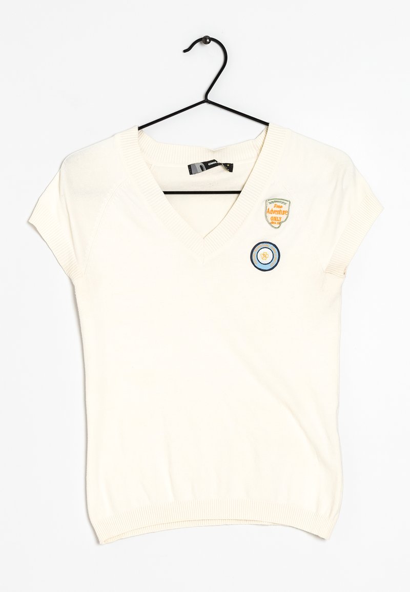 Suéter blanco de manga corta con escote en V, que presenta dos parches bordados: uno circular en azul y blanco, y una insignia rectangular de aventura.