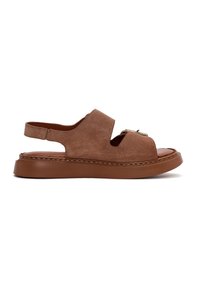 Sandal de ante marrón con un diseño recortado, correa para el talón ajustable y una suela de plataforma gruesa y texturizada en marrón. Presenta detalles de costura visibles.