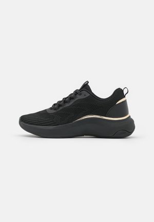 Czarny sportowy sneaker z siateczkową cholewką, sznurowaniem, grubą wyściółką podeszwy i złotym paskiem ozdobnym po zewnętrznej stronie.