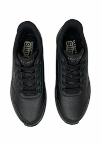 Paar schwarze Skechers-Leder-Sneaker mit Schnürsenkeln, gepolsterten Kragen und "Slip-On"-Einlegesohlen, von oben auf weißem Hintergrund gezeigt.