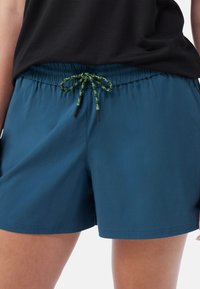 Blå shorts i lättviktsmaterial, med elastisk midja och en grön och svart dragsko, samt sidofickor.
