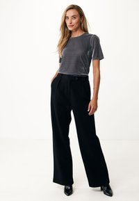 Grijze fluwelen top met korte mouwen gecombineerd met hoge taille zwarte wijde broek en zwarte puntige hakken, met een soepele textuur en gestructureerde pasvorm.