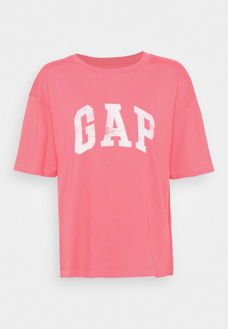 T-shirt en coton rose avec col rond, manches courtes et lettrage blanc "GAP" audacieux sur le devant. Texture lisse, coupe décontractée.