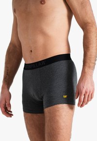 Shorts en coton gris avec une taille noire portant l'inscription "CATERPILLAR" et un petit logo jaune "CAT" en bas à gauche.