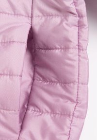 Tissu de doudoune rose clair en gros plan, présentant une texture matelassée, une finition lisse et une légère brillance avec des sections cousues délimitant la forme.