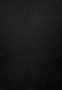 Svart tyg med en jämn, fint räfflad textur, jämnt vävd, som visar en lätt glans under ljuset, utan synliga mönster eller utsmyckningar.