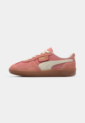 Sneaker in suede rosa e crema, con una parte superiore testurizzata, design con lacci e suola in gomma con branding impresso sul lato.