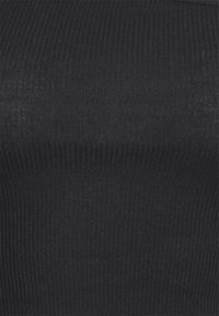 Svart ribbat tyg med en mjuk yta och vertikala linjer. Designen är figurnära och sömlös, med en svag lyster.