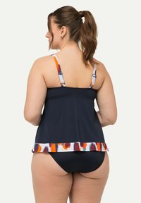 Ensemble de maillot de bain tankini avec un haut bleu marine foncé orné d'une bordure à motifs colorés et de bretelles réglables, associé à un bas bleu marine uni.