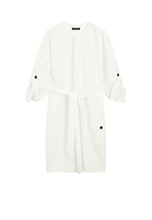Robe en coton blanc avec un col rond, des manches bouffantes 3/4 maintenues par des boutons noirs, une ceinture à la taille et une poche latérale.