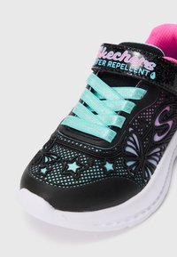 Zwarte sneaker van waterafstotend materiaal, met een mesh-design, turquoise veters, vlinder- en steraccenten, en een witte zool.