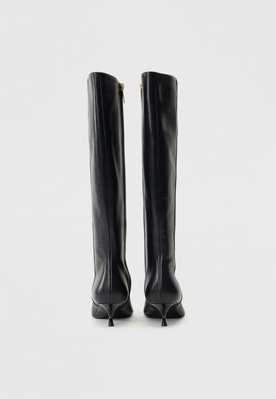 Kelių ilgio juodi odiniai batai su smailiu pirštu ir kreiviu kulnu, su užtrauktuku gale ir lygiu, blizgiu paviršiumi.