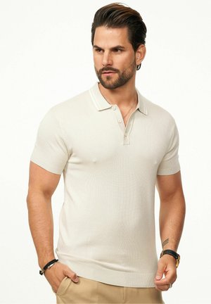 Short-sleeve, light beige polo shirt with a textured knit, two-button placket, and contrasting collar details. Subtle ribbed hem and cuffs.
