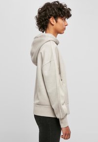 Felpa con cappuccio grigio chiaro realizzata in morbido materiale, caratterizzata da una vestibilità rilassata, cappuccio oversize e polsini e orlo a coste.
