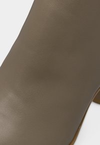 Κοντινή λήψη ομαλού καφέ δερμάτινου υλικού στο επάνω μέρος υποδήματος με ορατή υφή κόκκου και διακριτική λάμψη.