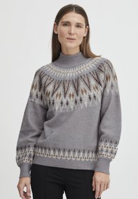 Grijze gebreide trui met een hoge halslijn, voorzien van een geometrisch patroon in tinten bruin en crème langs de schouders en manchetten.
