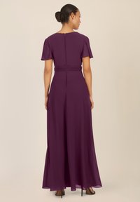 Vestido largo púrpura con mangas cortas y cintura ceñida. Tejido suave con una falda fluida y cierre de cremallera en la parte posterior.