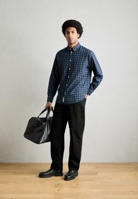 Button-up Hemd mit blauem und grünem Karomuster, schwarze Hose, schwarze Lederhandtasche und Schuhe. Glatter Stoff, taillierte Passform.